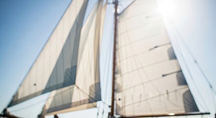 Sails of a sailboat against a bright blue sky on a sunny day.
