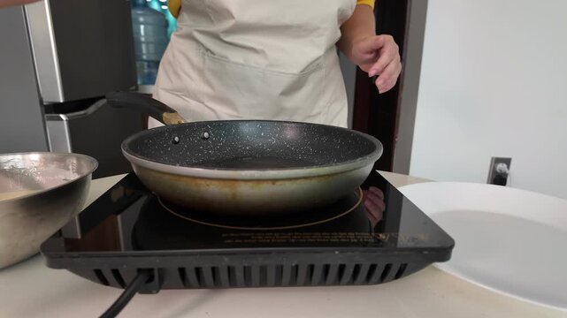 A woman cooks pancakes in a frying pan, cooks in a kitchen