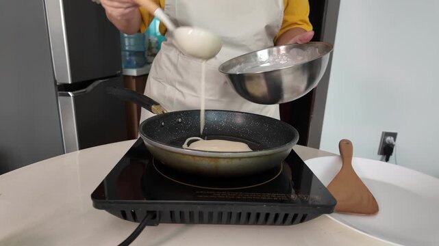 A woman is frying pancakes at home in the kitchen on an induction hob.