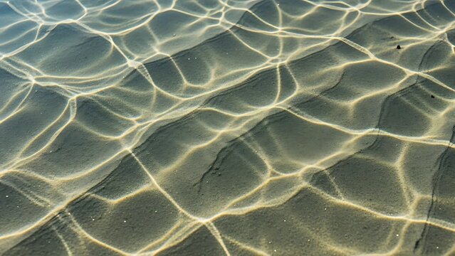 Serene water surface with sunlight reflections on sandy bottom creating a mesmerizing pattern of light and shadow
