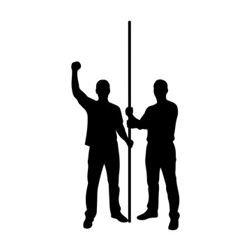 Silhouette of two men holding a pole.