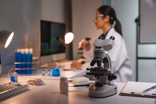 Microscope on lab desk with scientist working