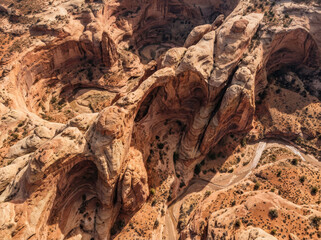 Obraz premium Aerial view of a vast desert canyon with intricate rock formations and a winding road below.