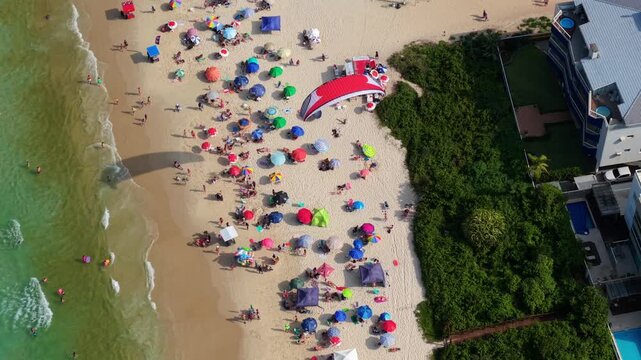 Top-Down Aerial view of Powered Paragliding Over Crowded Praia dos Ingleses, Florianopolis, Brazil, Summer Adventure Sport