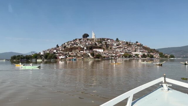 Boat view approaching Janitzio Island with hillside homes and statue on Lake Patzcuaro