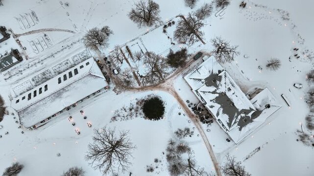 A cinematic rising drone shot capturing the snowy roof and grounds of Abgunste Manor in Jelgava district, Latvia. This 18th-century cultural monument is shown nestled in a pristine winter landscape.