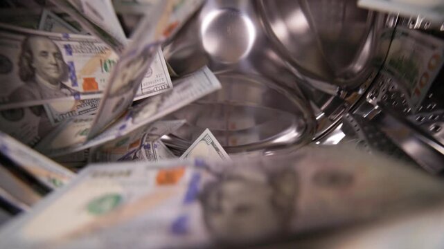 US cash spinning inside a washing machine in slow motion wide angle closeup view. Money laundering concept.