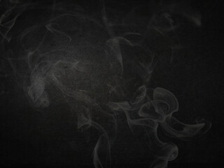 Wispy white smoke fog plumes gracefully ascend against a deep black background