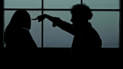Naklejka premium Husband Accusing wife with Finger Pointed in Dramatic Silhouette