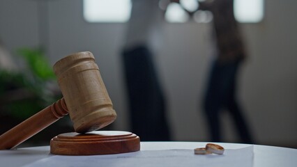 Judge Gavel on Table with Wedding rings and Blurred Couple Arguing
