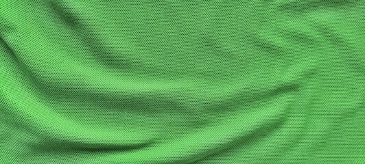 Green sports jersey fabric texture close up. Soft football clothing textile background. Sports wear background with smooth green fabric detail.