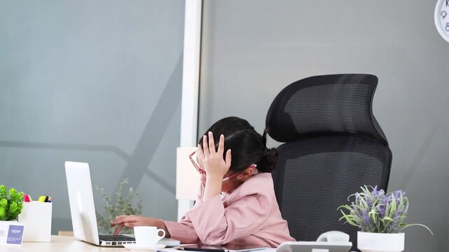 Young Asian Girl in Pink Suit Working at Office Desk with Laptop