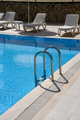 Pool area with comfortable sun loungers. Empty hotel pool. Summer vacation resort concept.