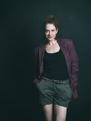 Naklejka premium Low-Key-Portrait eines Models im Mantel vor dunklem Hintergrund. Dramatisches Licht, starke Schatten und roter Lippenstift setzen elegante, ausdrucksstarke Akzente.