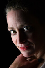 Naklejka premium Low-Key-Portrait eines Models im Mantel vor dunklem Hintergrund. Dramatisches Licht, starke Schatten und roter Lippenstift setzen elegante, ausdrucksstarke Akzente.