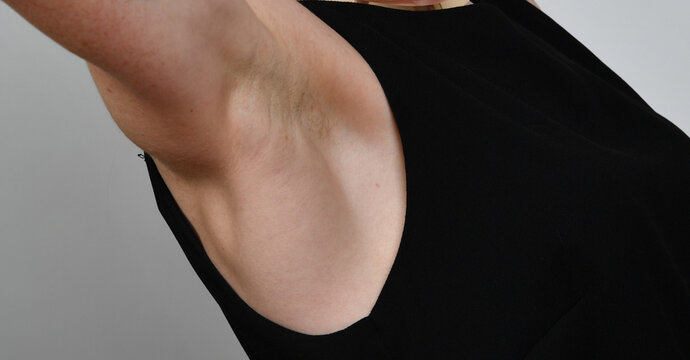 Detailaufnahme einer weiblichen Achsel in schwarzem Top. Minimalistische Studiofotografie zum Thema K&ouml;rperpflege, Nat&uuml;rlichkeit und moderne Body-Positivity.