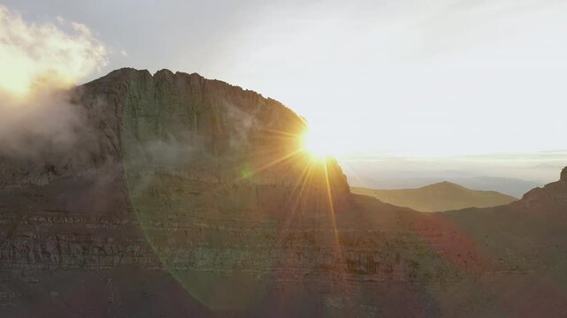 Drone shot capturing the sun emerging behind the Throne of Zeus on Mount Olympus, Greece during sunset