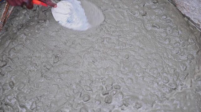 Close-up of a construction worker using a hand trowel for freshly poured Concrete Finishing at building site. day time, stable shot, 4k.