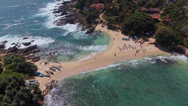 Drone view over blue beach in Sri Lanka in the morning as people walk across the sand bank