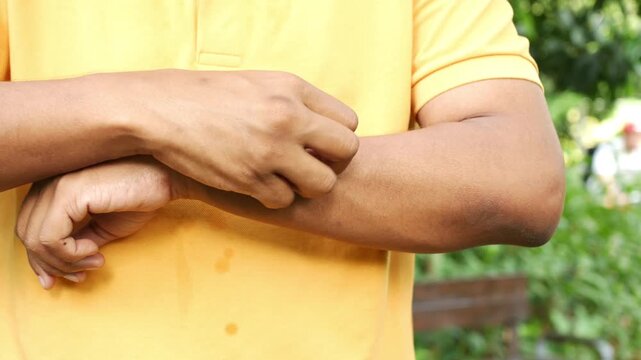 Person scratching arm in outdoor setting slow motion