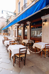 Outdoor cafe seating with tables and chairs on a quiet street in the daytime