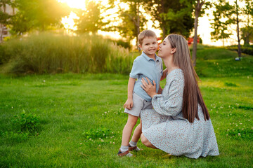 Fototapeta premium mom and child playing on a green lawn in the park in the summer, having fun together, mother and small child walking in the summer, playing on the grass