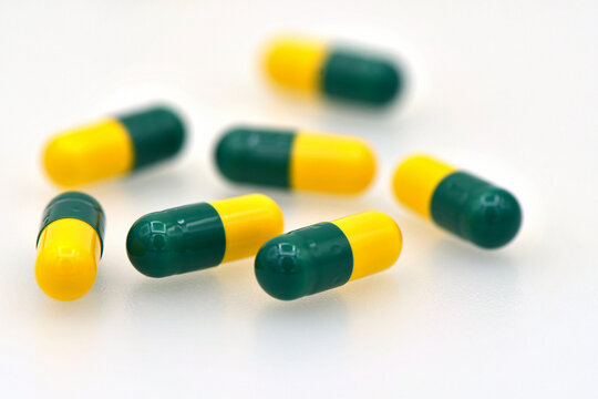 Green and yellow Tramadol capsule pills isolated on white background.