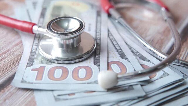 Stethoscope on money for medical expense, health insurance concept with doctor instrument on cash bills, high angle moving footage