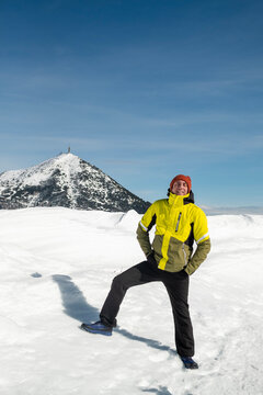 Tourist portrayed on a snow-capped mountain. The man is forty-two years old, of Caucasian origin and wears a yellow and green ski jacket