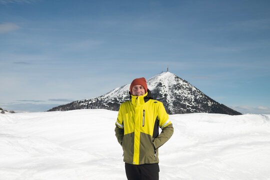 Tourist portrayed on a snow-capped mountain. The man is forty-two years old, of Caucasian origin and wears a yellow and green ski jacket