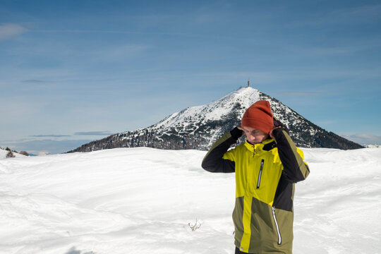 Tourist portrayed on a snow-capped mountain. The man is forty-two years old, of Caucasian origin and wears a yellow and green ski jacket