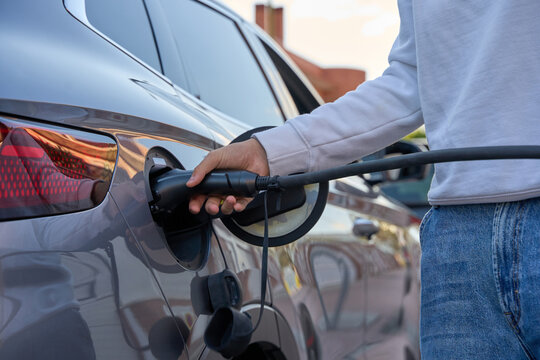 Person charging electric vehicle at outdoor station