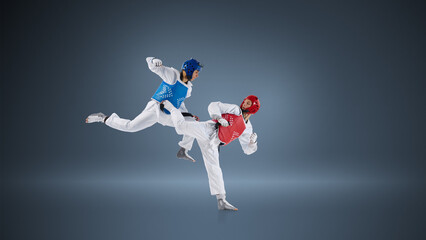 Naklejka premium Professional taekwondo fighters in dynamic kick exchange on blue background wearing protective helmets and chest guards. Concept of elite combat sport, competitive sparring and athletic performance.