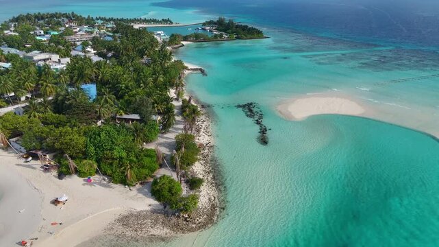 Maldives scenic aerial drone shot over a beautiful local island showing dense green vegetation, white sandy shores, and vibrant blue reef water. Tropical travel destination, Mathiveri.