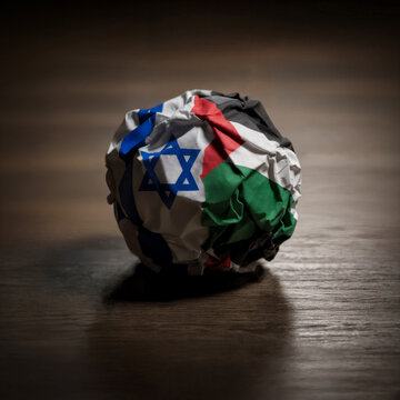 crumpled paper ball with image of flags of israel and palestine on wooden table symbolizing fragility of peace and unresolved territorial dispute