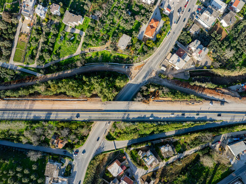 Aerial view of a highway cutting through vibrant green vegetation and connecting roadways, a concrete artery amid nature's sprawl, Chania, Chania, Greece.