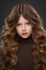 Studio portrait of a beautiful young girl with long wavy hair, dark background © Alexander