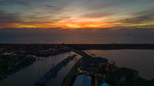 Aerial view of the Coronado Island under a radiant sky ablaze with orange and yellow hues meeting the dark blue waters, Coronado, California, United States.