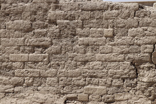 Old cracked adobe brick wall showing weathered texture outdoors