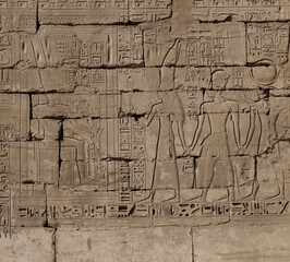 Obraz premium Ancient Egyptian wall carving depicting figures and hieroglyphs outdoors