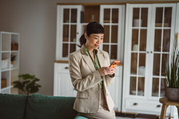 Fototapeta premium Asian business woman using smart phone communicating in office