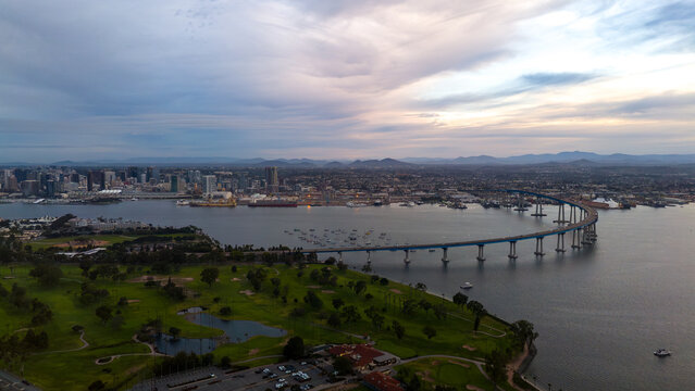 Aerial view of the iconic Coronado Bridge elegantly arches across the bay towards the distant city skyline, a serene blend of urban and natural beauty, Coronado, California, United States.