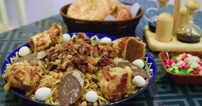 Close-up of Uzbek plov served on table with meat, kazy, quail eggs and raisins