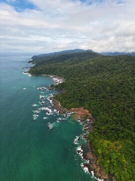 Aerial view of the rugged coastline where the verdant forest meets the turquoise sea, creating a stunning contrast of colors and textures, Puerto Viejo de Talamanca, Costa Rica.
