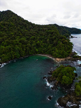Aerial view of the jagged coastline where the dense jungle meets the sea, its dark greens sharply contrasting the turquoise waters, Mutis, Choco, Colombia.