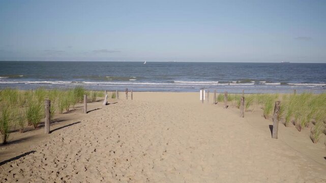 Slow walk towards sandy beach with sail boat and dune grass in Knokke Belgium
