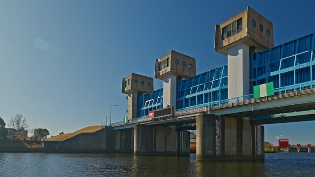 A detailed shot of the Blue Iwabuchi Sluice Gate towers and the bridge structure over the water, highlighting the engineering details and the bright blue color of the gate.