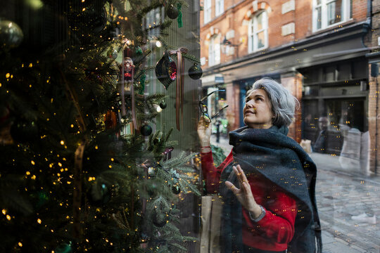 Woman shopping and admiring festive Christmas window display in city