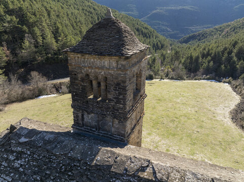 Aerial view of a stone tower rising majestically against the backdrop of rolling hills and valleys, a contrast of textures and tones, Oros Bajo, Aragon, Spain.