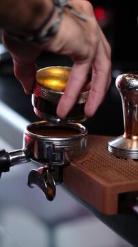Cinematic close-up of barista leveling coffee grounds in portafilter